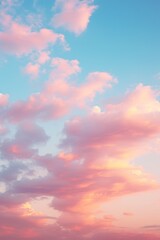 Fototapeta premium A dramatic cloudscape at sunrise with pink and golden glowing clouds against a clear blue sky