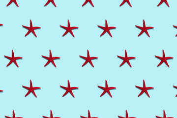 Creative red starfish pattern on blue background. Summer minimal concept.
