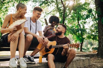 Interracial street performers sitting in a park and jamming.