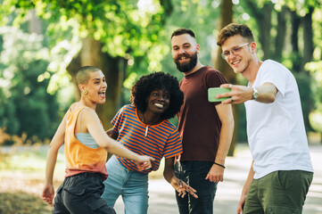 A young multicultural tourists taking selfies in city park.