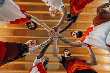 Low angle shot of a diverse professional basketball team joining hands