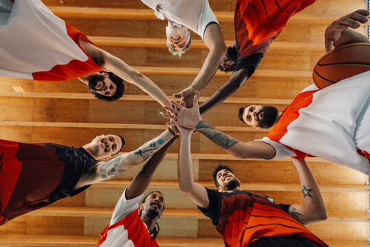 Low angle shot of a diverse professional basketball team joining hands