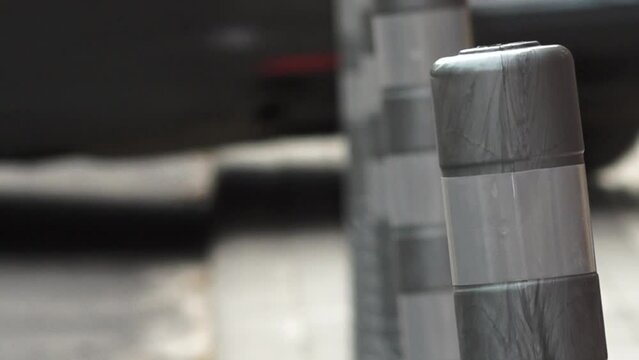 Close-up of gray plastic bollards lined up on a sidewalk, creating a pattern and providing safety and separation from the street.