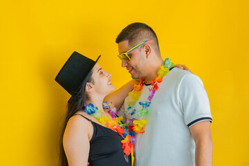 young latin couple, facing each other smiling while dressed in party clothes, yellow background....
