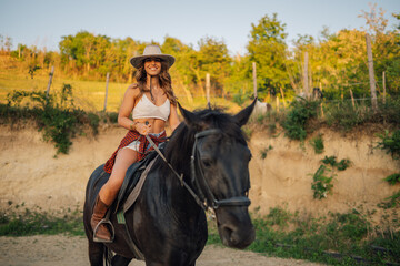 Portrait of cowgirl horseback riding a horse at rural homestead.