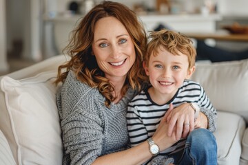 Obraz premium Single mother and son portrait. Adorable boy hugging his single mother in the living room. Happy mom and her loving son enjoying weekend leisure time.