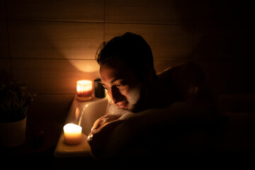 Handsome man bathing in the candlelight. Self care and spa concept	