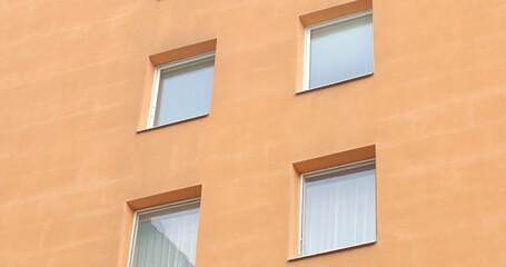 Obraz premium City living. Orange facade of a multi-story residential panel building. Witness the architectural symmetry and vibrant community life. Modern urban landscape. 