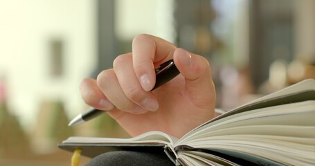 Close-up of hand twirling a pen, clicking its cap in a rhythmic motion. Action symbolizes the...