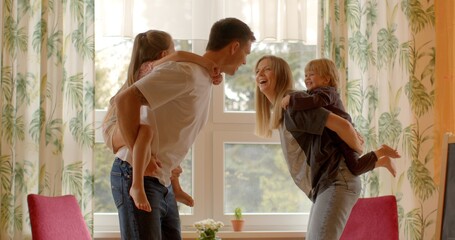 Playful interaction Parents playfully engage with their young children, carrying them on their...