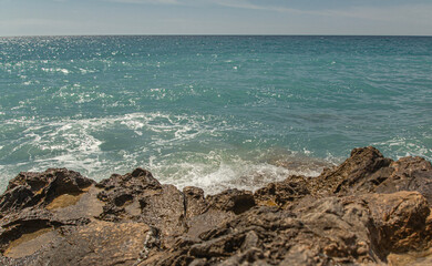 Glare on the water, beautiful granite stones in the foreground of the Mediterranean landscape. splashes of water. sunny day