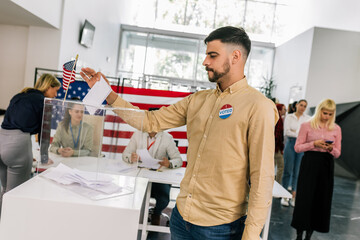 Voter placing ballot in ballot box polling place