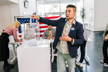 Asian voter in America placing ballot in ballot box polling place.