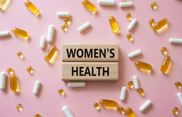 Womens health symbol. Concept word Womens health on wooden blocks. Beautiful pink background with pills. Medicine and Womens health concept. Copy space