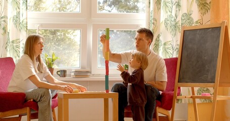 Dad, mom, and little child playing at home. Playful activities together. Concept of family bonding,...