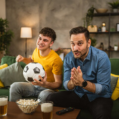 Young and adult man friends watch football match and cheer at home