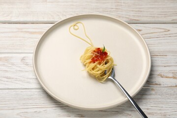 Heart made with spaghetti and fork on white wooden table