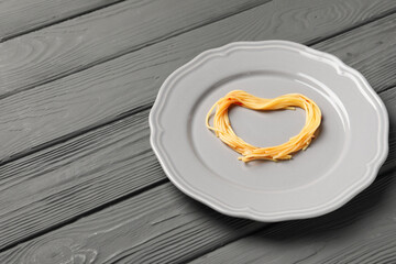 Heart made with spaghetti on grey wooden table