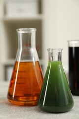 Flasks with different types of crude oil on light grey table