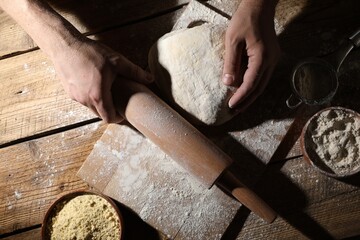 Man making dough at wooden table, top view