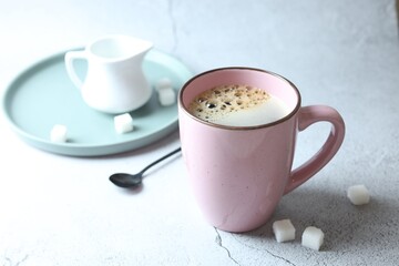 Tasty coffee in cup and sugar cubes on white textured table, closeup