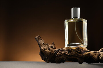 Luxury men`s perfume in bottle on grey table against brown background, space for text