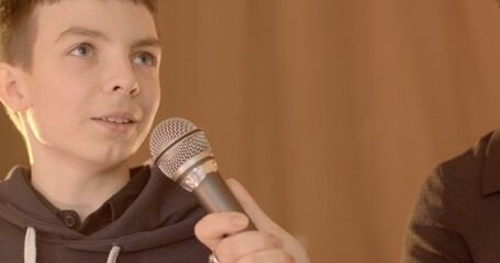 Close-up teenage student speaks into microphone during school debate. 7th grader confidently...