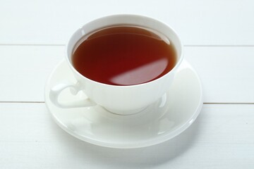 Aromatic tea in cup on white wooden table
