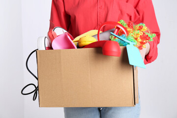 Woman holding box of unwanted stuff on white background, closeup