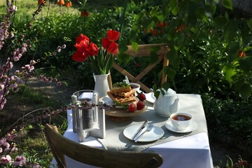 Beautiful bouquet of tulips and freshly baked waffles on table served for tea drinking in garden