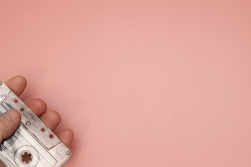A classic 1990's cassette tape on a pink background being held by a mans hand retro vintage music...