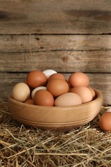 Fresh chicken eggs in bowl on dried straw bale