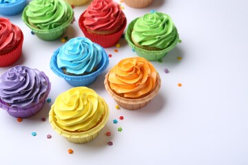Many tasty cupcakes with bright cream and sprinkles on white background. Space for text