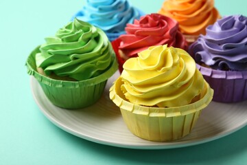 Plate with delicious bright cupcakes on turquoise background, closeup