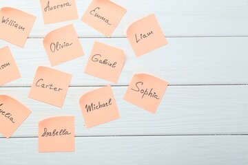 Choosing baby's name. Paper stickers with different names on white wooden background, flat lay. Space for text