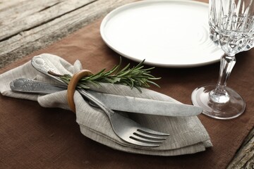 Stylish setting with cutlery, glass and plate on wooden table, closeup