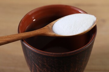 Glass of water and spoon with baking soda on table, closeup