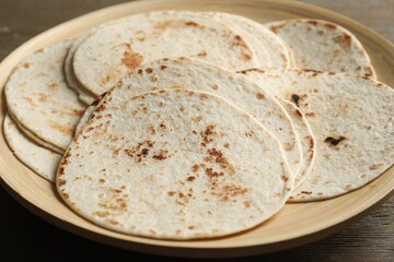 Many tasty homemade tortillas on wooden table, closeup