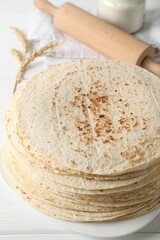Tasty homemade tortillas, spikes and rolling pin on white wooden table