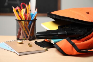 Gun, bullets and school stationery on wooden table indoors, closeup - Powered by Adobe