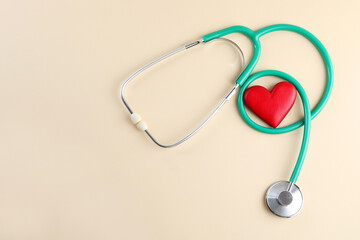 Stethoscope and red heart on beige background, top view. Space for text