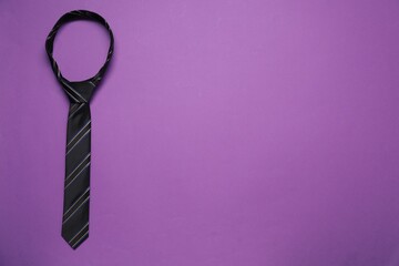 Striped necktie on purple background, top view. Space for text