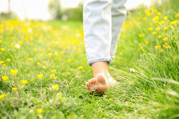 Woman walking barefoot on green grass outdoors, closeup