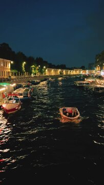 Russia, April 9, 2024: Boats on the canal in St. Petersburg in spring. Bridges and historical buildings on the river embankment, people walking along the embankment. Reflections of houses in the water