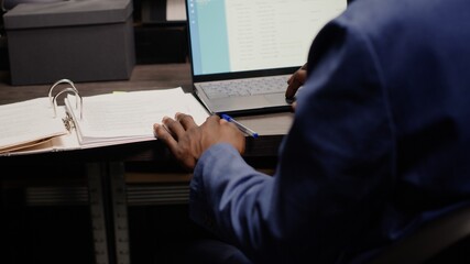 Detective captured in midst of investigation, analyzing records and evidence. Detailed view of...