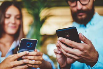 Selective focus on male and female hands holding smartphone devices and messaging with friends...