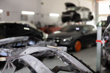 Close-up of sanded car part, prepared for painting, and sandpaper in auto repair shop, with blurred...