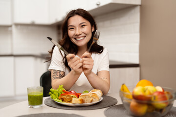 Happy Young Woman Enjoying A Healthy Meal In A Modern Kitchen, Smiling Joyfully With Fork And...