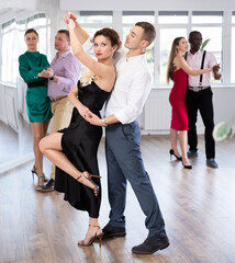 With unhurried music, man with woman in couple spins to rhythm of waltz during lesson for novice...
