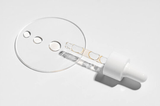 Cosmetic serum bottle with dropper on white backdrop